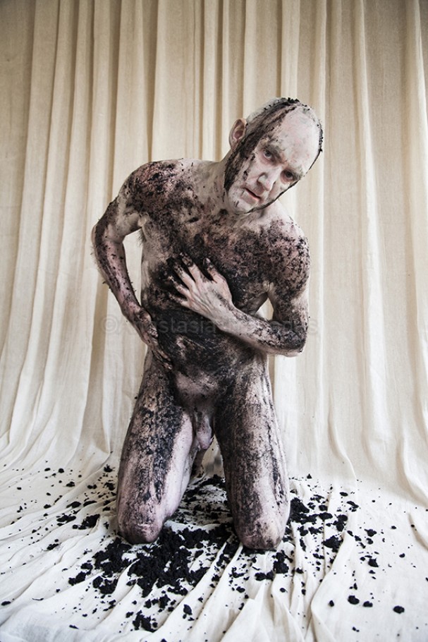 Naked man covered with dirt