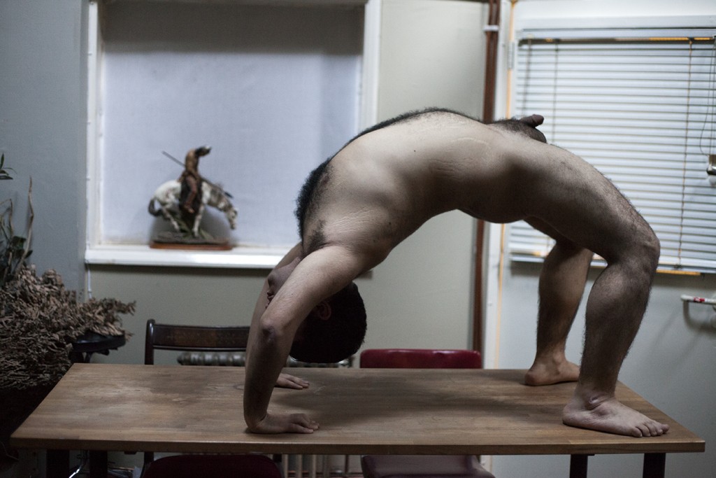 Naked man doing yoga on table